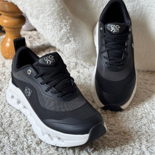 Black and white sneakers on a textured surface with a wooden object in the background